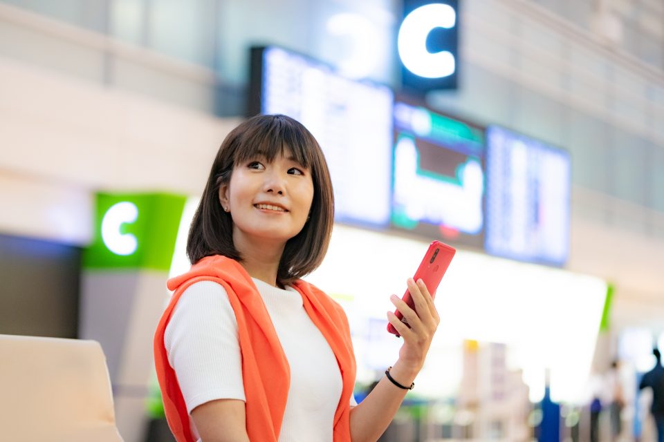 海外の空港でスマホを使う女性